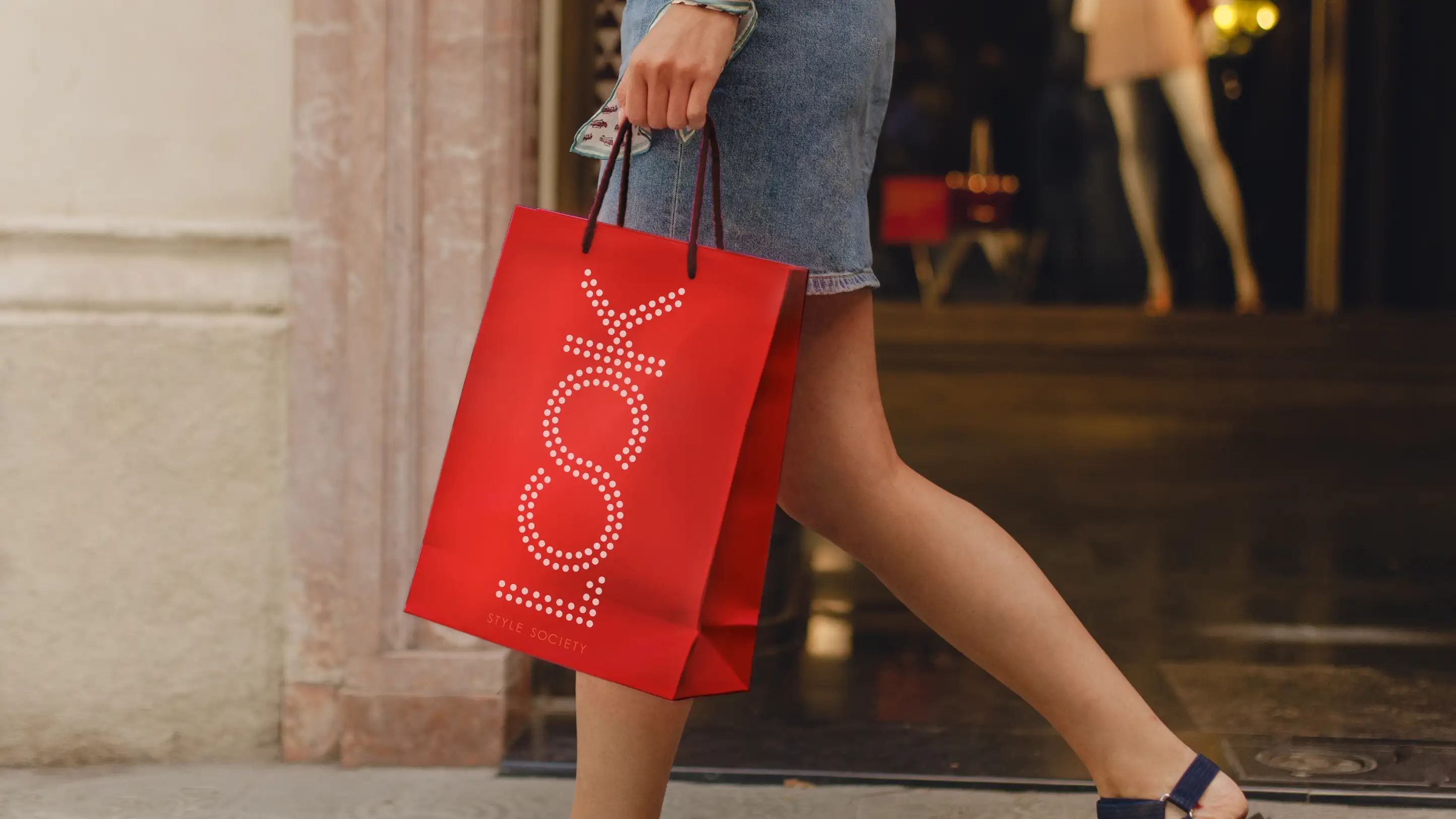 Look Style Society logo on a red shopping bag, being carried through outdoor shopping center.