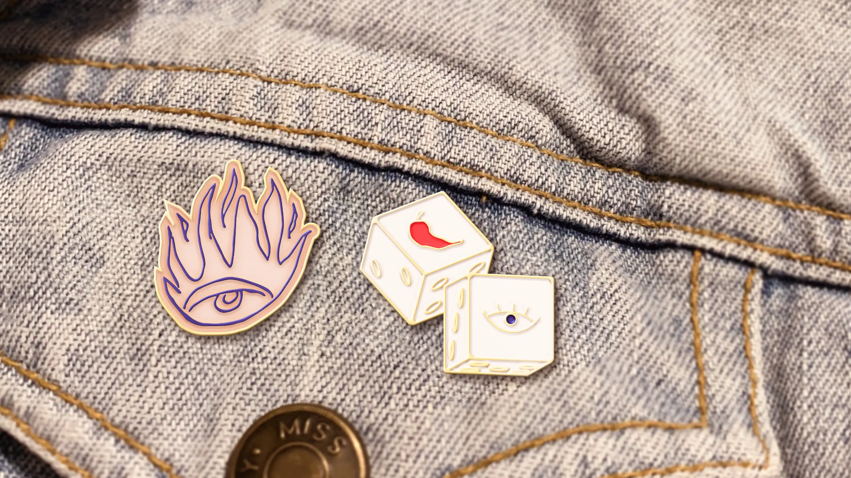 Closeup of Spicy Eyes enamel logo pins on blue jean jacket pocket.